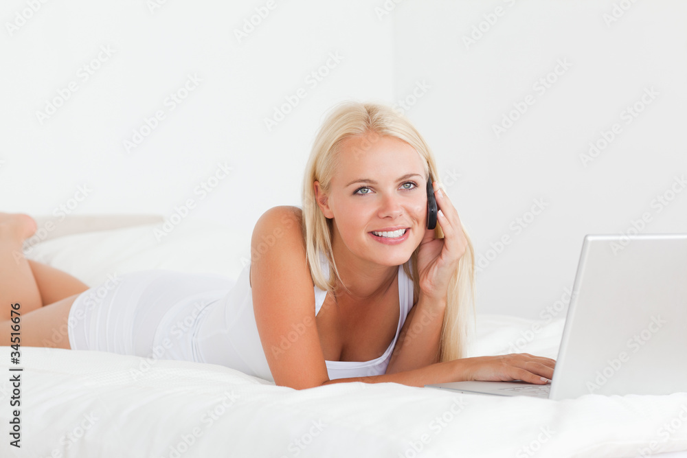 Smiling woman on the phone with a laptop Smiling woman on the phone with a laptop