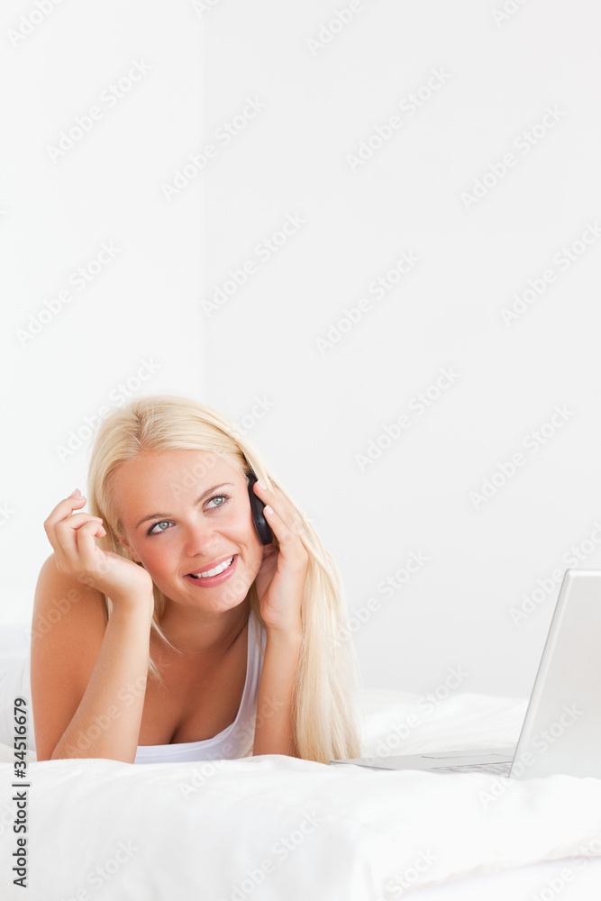 Obraz premium Portrait of a woman speaking to the phone with a laptop