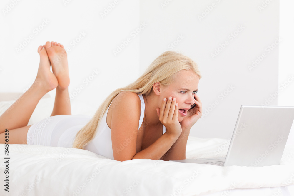 Obraz premium Upset woman on the phone while using a laptop