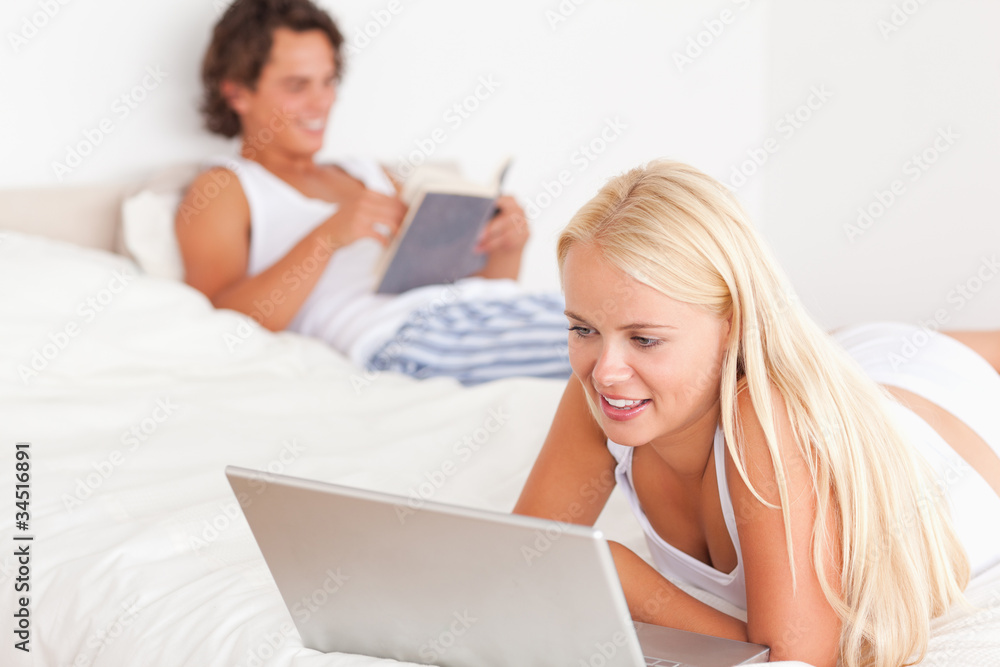 Woman using a notebook while her fiance is reading Woman using a notebook while her fiance is reading