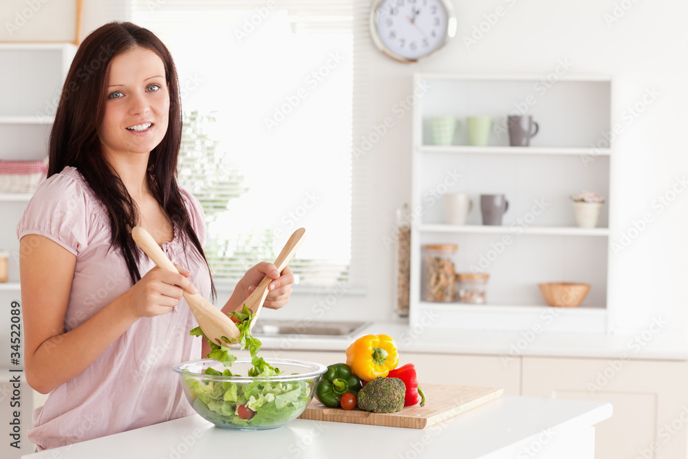 Red-haired woman mixing a salad looking into the camera