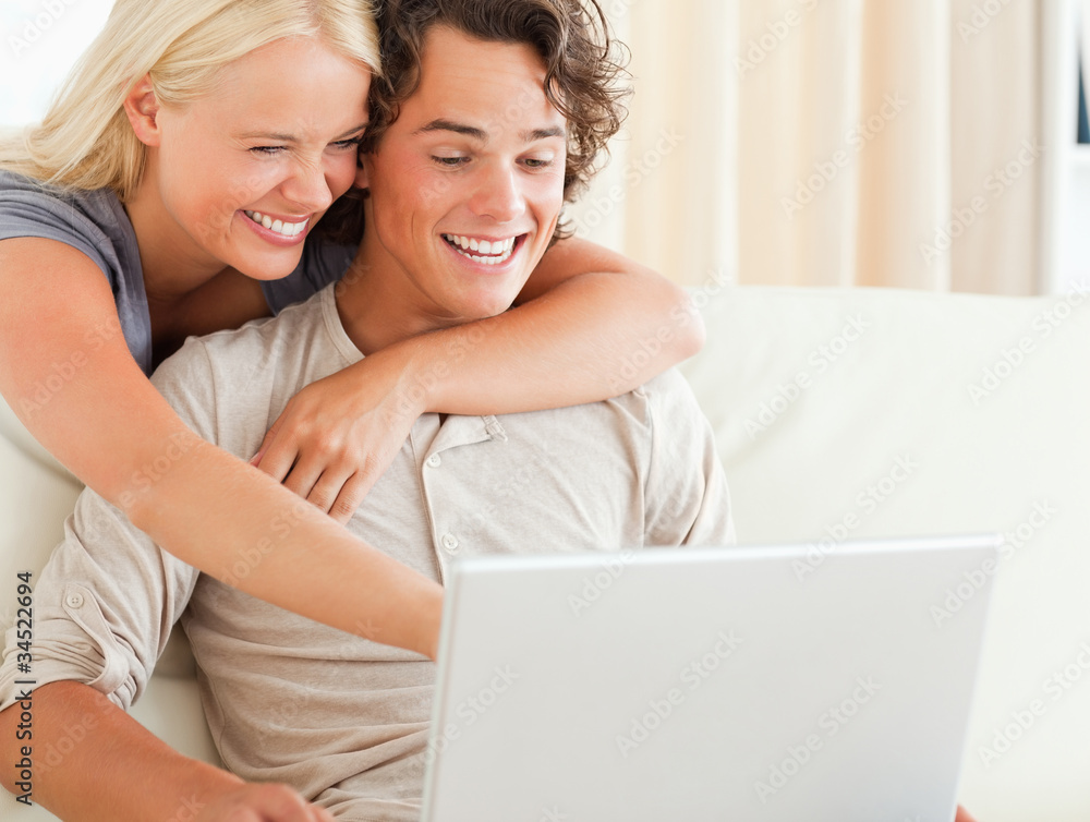 Laughing couple using a laptop