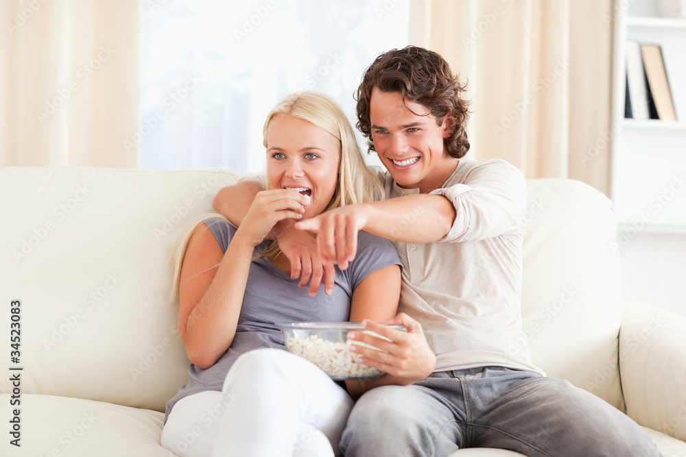 Couple watching TV while eating popcorn Couple watching TV while eating popcorn