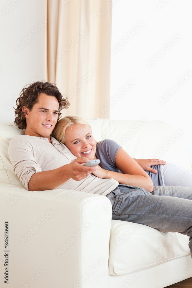 Portrait of a couple cuddling while watching TV Portrait of a couple cuddling while watching TV