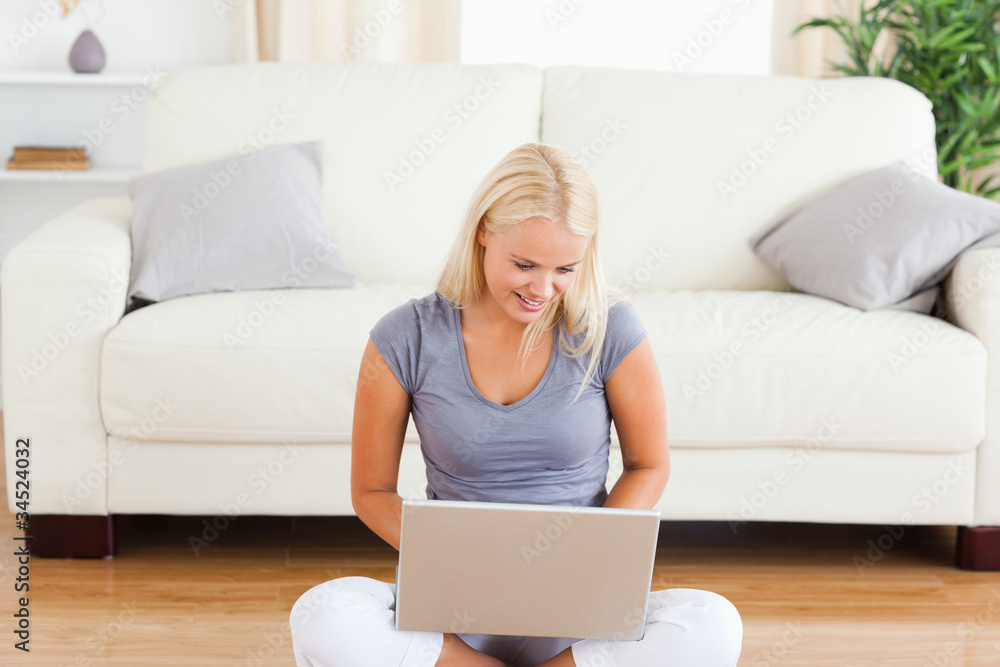 Happy woman using a notebook while sitting on the floor Happy woman using a notebook while sitting on the floor