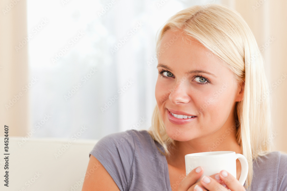 Close up of a woman sitting on a couch with a cup of coffee