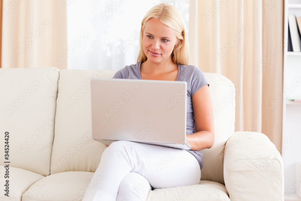 Woman sitting on a sofa while using a laptop Woman sitting on a sofa while using a laptop
