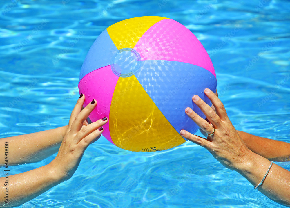 hands of mother and daughter playing with Beach ball in pool