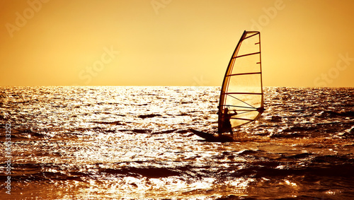 Obraz na płótnie Windsurfer silhouette over sea sunset