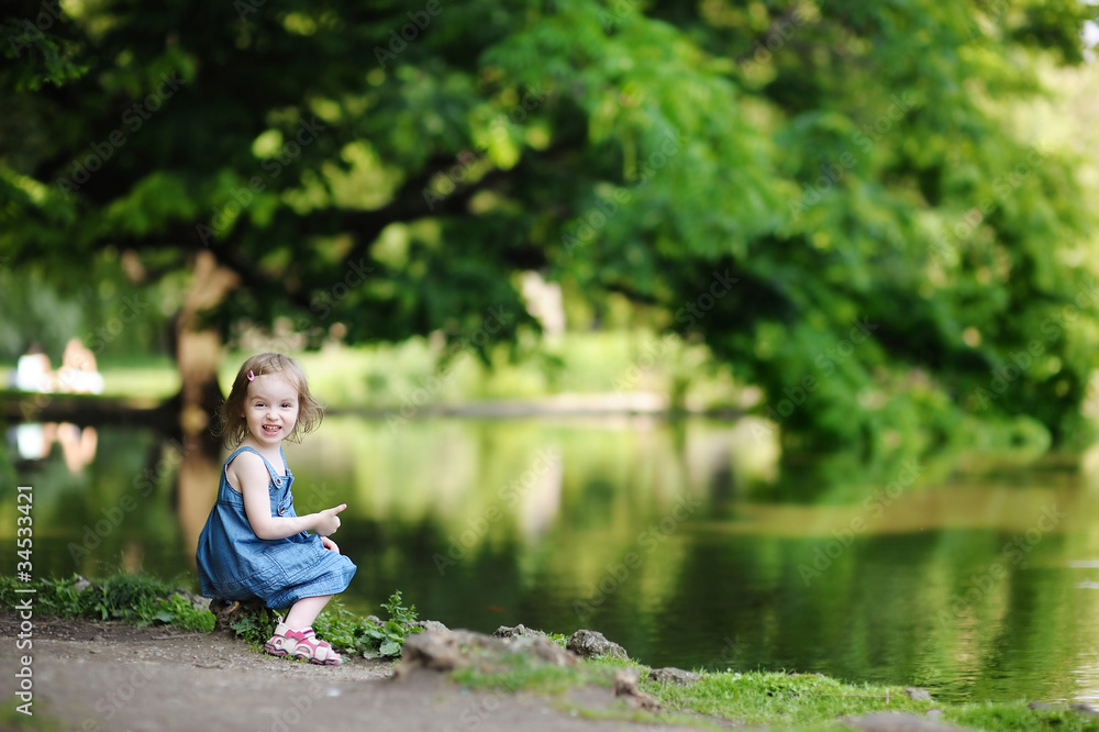 Adorable little girl sitting by the water Adorable little girl sitting by the water