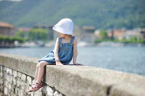 Little girl sitting on a stone parapet