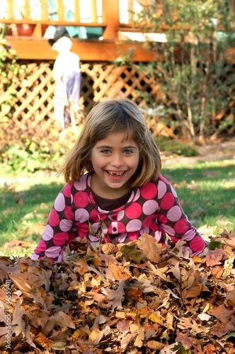 Young girl plays in a pile of leaves