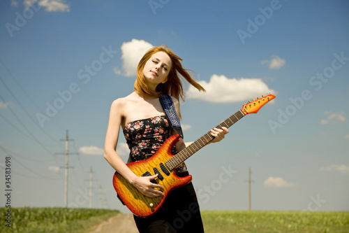 Rock girl with guitar at countryside.