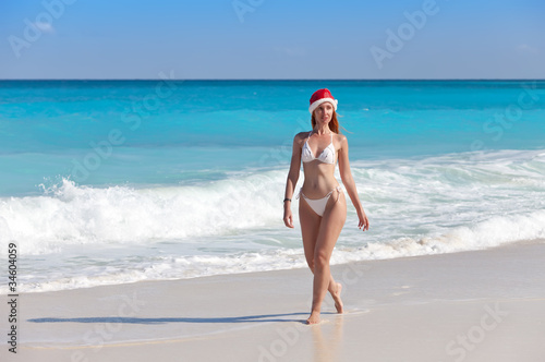 The young woman in a hat of Santa Claus on beach