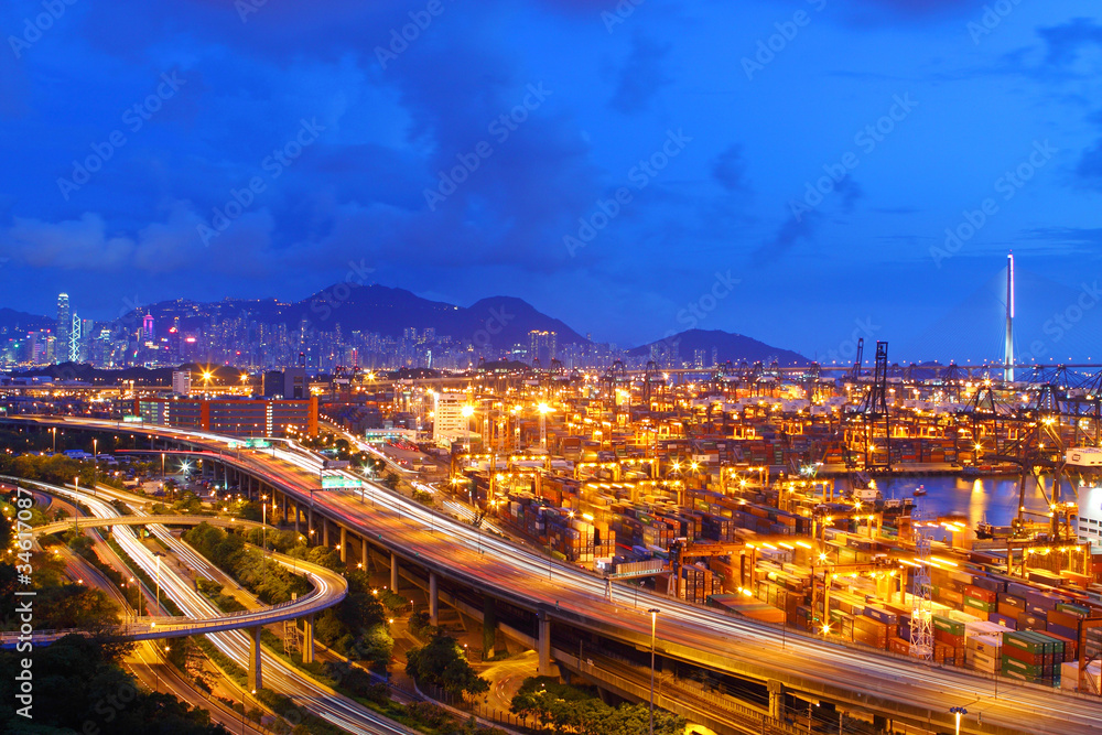 Busy traffic in Hong Kong at night with container terminal backg
