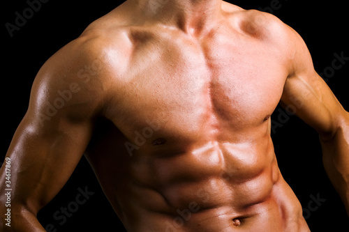 Beautiful naked male torso against black background