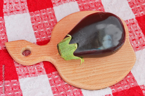 An eggplant on a wooden cutting board