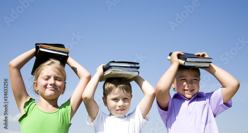 Image of three children holding books over their heads