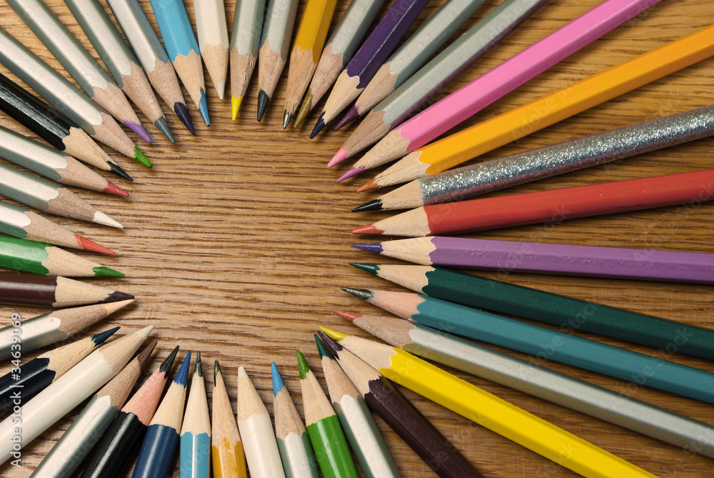 Set of pencils in a circle on a wooden background.