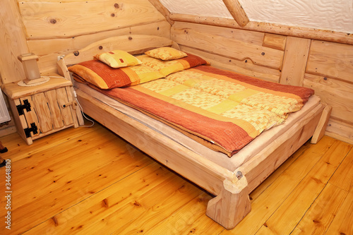 Wooden rustic bed in country cottage bedroom.