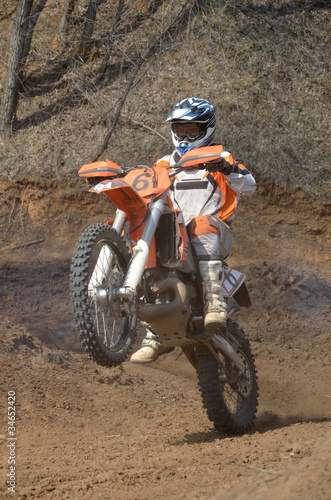 Motocross rider on a motorcycle rides on the rear wheel