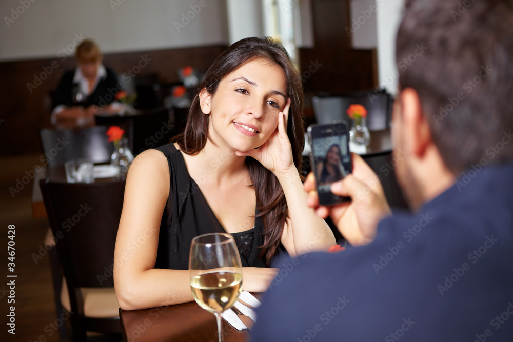 Mann fotografiert Frau in Restaurant