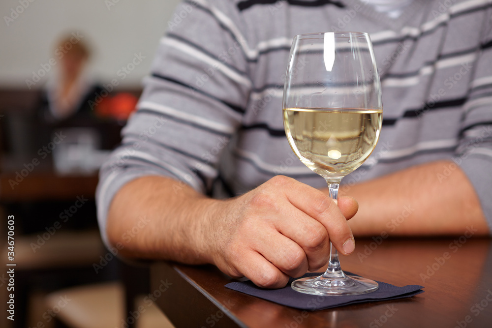 Hand hält Glas mit Weißwein