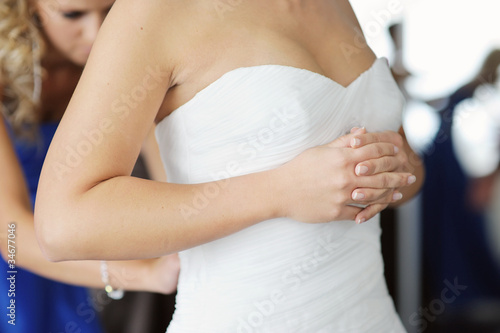 Bride's hands while putting wedding dress on
