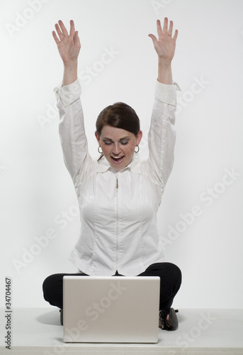 Young Woman with her Hand Raised in front of a Laptop Computer © ToddKuhns