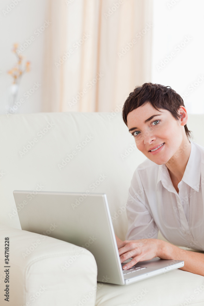 Cute Woman lying on a sofa with a laptop