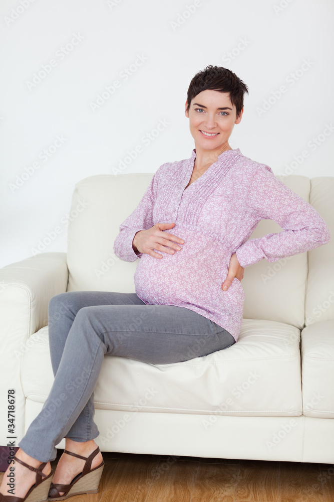 Smiling pregnant woman sitting on a sofa Smiling pregnant woman sitting on a sofa