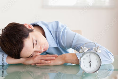 Photos Sleeping businesswoman with her head on the desk next to an alar