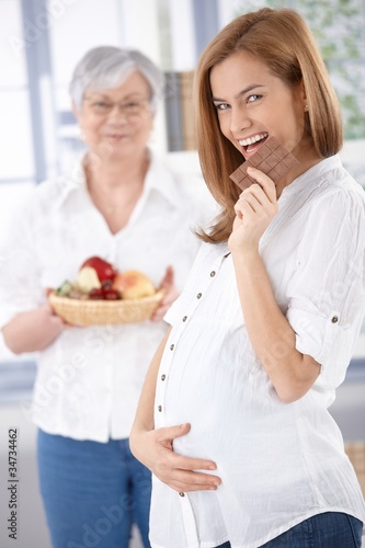 Happy pregnant woman eating chocolate