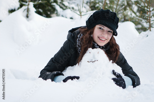 Junge sympatische Frau mit Zahnspange baut einen Schneemann