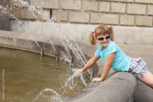 Girl playing with water from a fountain