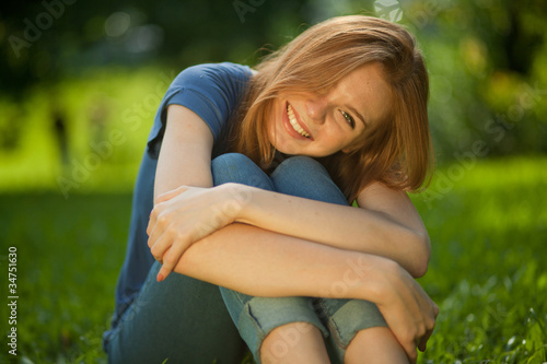 beautiful red-haired girl sitting on grass