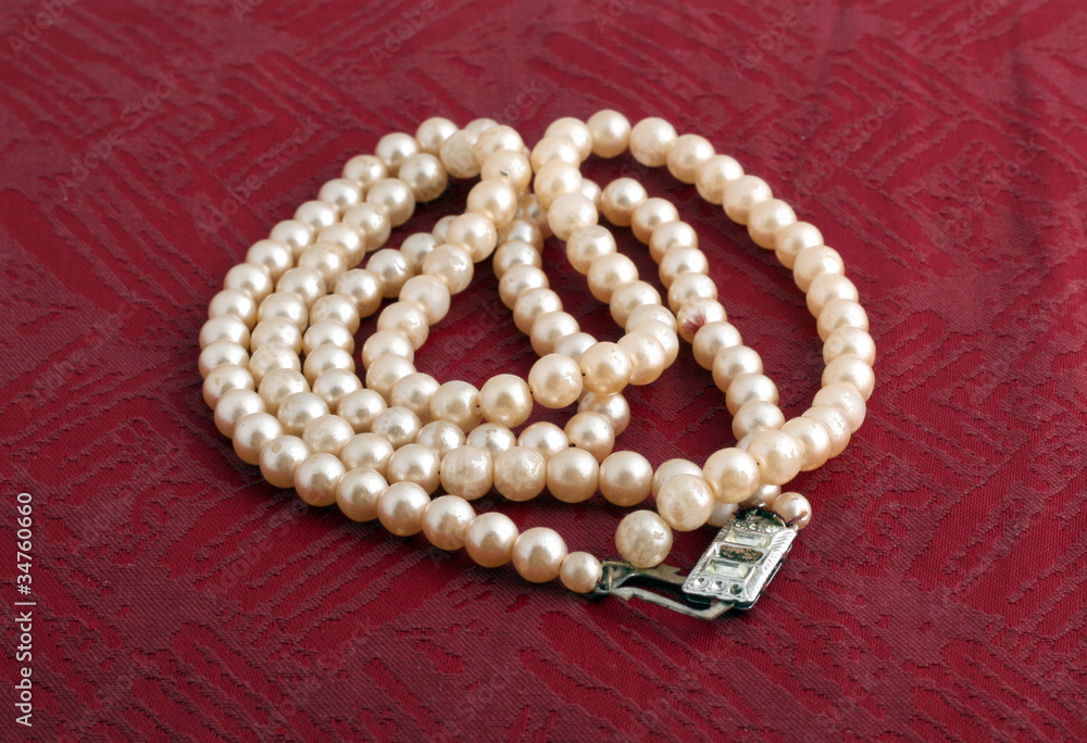 Fototapeta premium White pearl necklace on red background.
