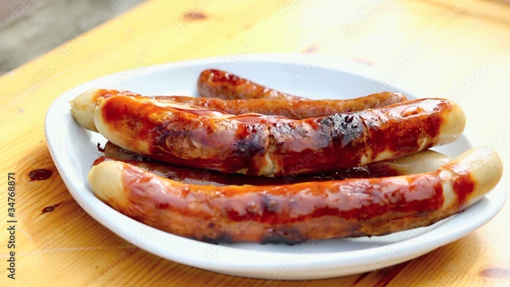 Bratwurst wird mit einer Zange genommen Bratwurst wird mit einer Zange genommen