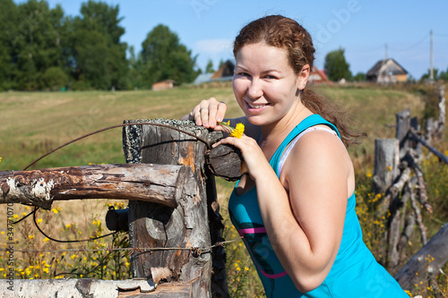 One young Caucasian Russian woman near village fence