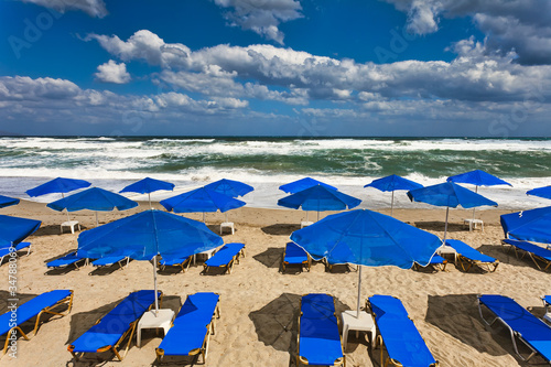 Blue parasols at an empty, stormy beach