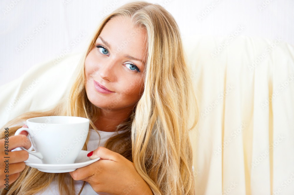 Young woman at home sipping tea or coffee from a cup Young woman at home sipping tea or coffee from a cup