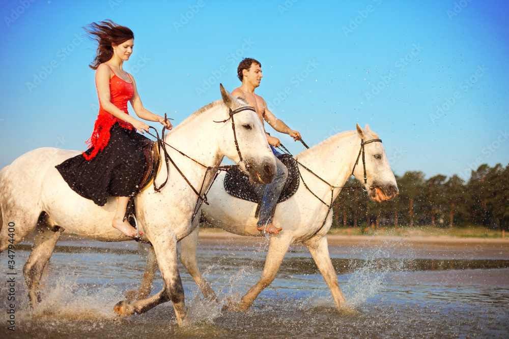 Young couple in the sea on horseback Young couple in the sea on horseback