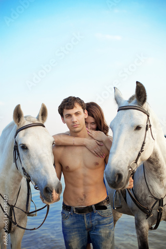 Young couple in the sea with horses