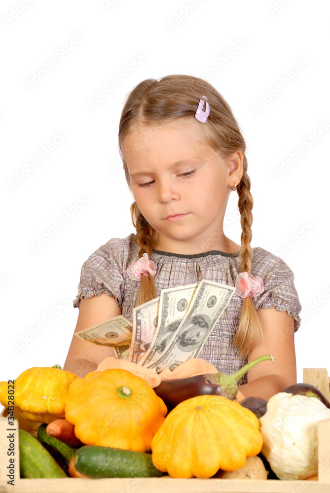 Fototapeta premium Sad little girl counts money and vegetables isolated on the whit