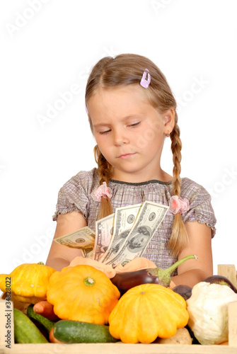 Sad little girl counts money and vegetables isolated on the whit