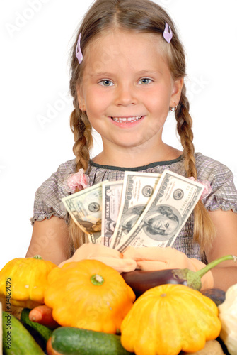 Little girl counts money and vegetables isolated on the white