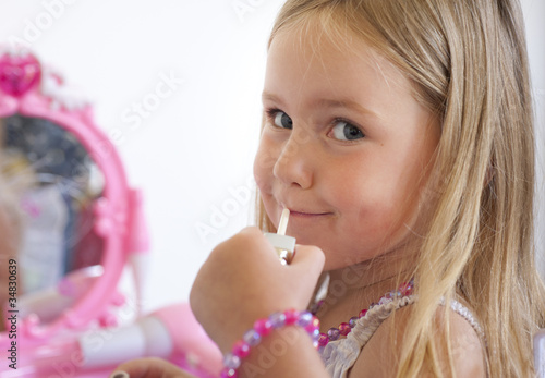Принти на полотні little girl pretending to put on lip gloss
