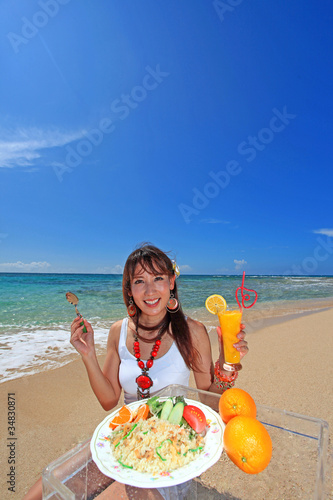 浜辺で昼食を取る笑顔の女性