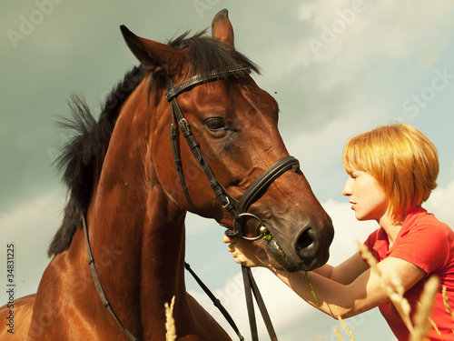 young girl with horse at cloudy sky background