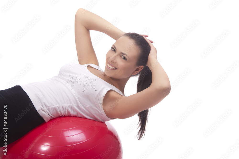 Fototapeta premium pretty brunette girl laying down on red fitball and smiling
